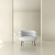Modern white accent chair with curved backrest and black legs in a minimal, neutral interior